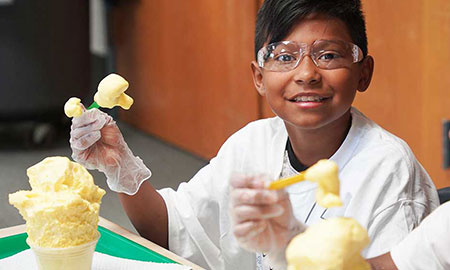 An elementary school student poses with his Matter Monsters experiment